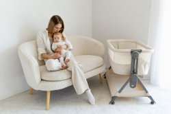 mama-z-dzieckiem-na-kolanach-siedząca-na-sofie-obok-łóżeczko-dostawne